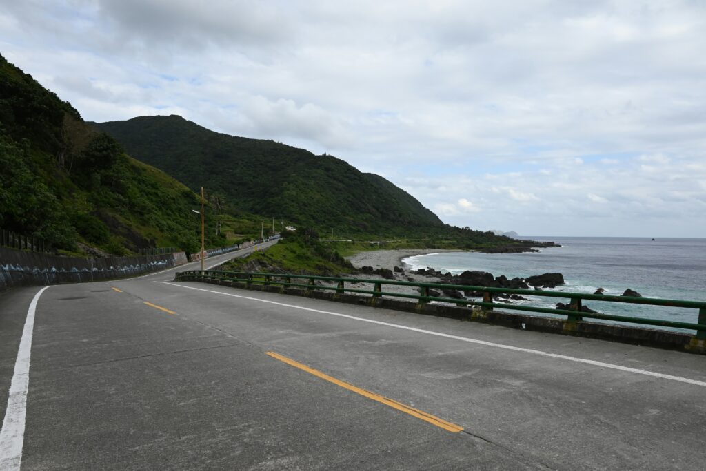 海沿いをゆるやかに曲がる道路と、緑豊かな山々が続く静かな風景